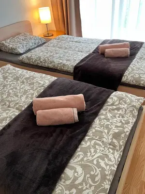 three beds with towels on them in a room at Golden Fox Apartment Pohorje in Maribor