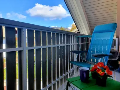 a blue chair on a porch with a table and flowers at Apartma DAVID in Zgornje Gorje