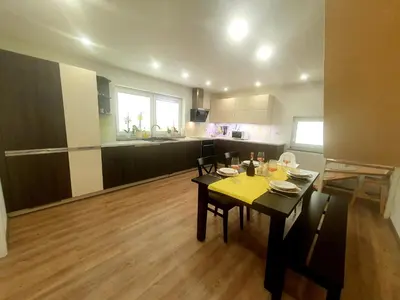 a living room with a table and a kitchen at Apartma DAVID in Zgornje Gorje