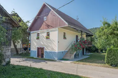 a white and blue house with flowers on the windows at Apartments in Stari trg ob Kolpi - Süd-Ost Slowenien 42908 in Stari Trg ob Kolpi