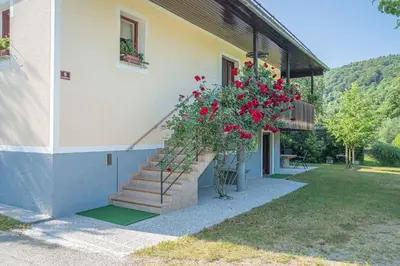 a building with a staircase with red flowers on it at Apartments in Stari trg ob Kolpi - Süd-Ost Slowenien 42908 in Stari Trg ob Kolpi