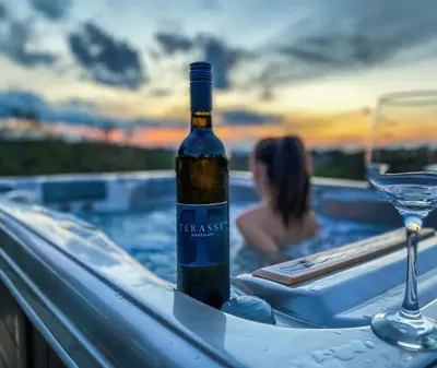 a bottle of wine sitting on a table in a bath tub at Wellness hiška Robida in Ljutomer