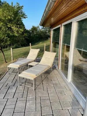 two lounge chairs sitting on a patio next to a window at Wellness hiška Robida in Ljutomer
