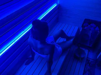 a person sitting on a bench in a dark room at Wellness hiška Robida in Ljutomer