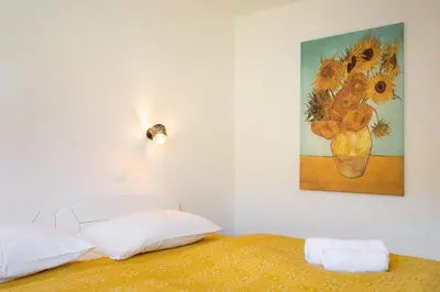 a bedroom with a painting of a vase of sunflowers at APARTMENT 396 in Ljubljana
