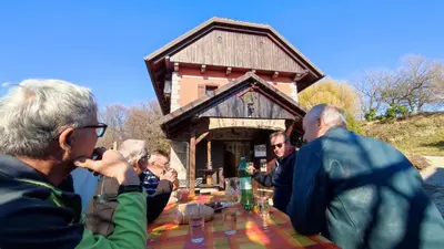 a group of people sitting at a table in front of a building at Apartman Vesna in Veliki Vrh