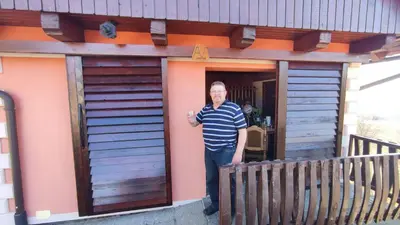 a man standing in the doorway of a tiny house at Apartman Vesna in Veliki Vrh