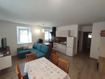 a living room and kitchen with a blue couch and a table at Apartma Moser in Podnanos