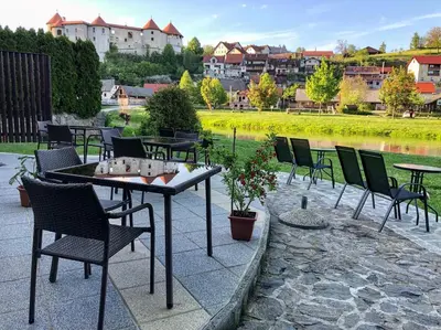 a patio with tables and chairs next to a river at Gostišče Koren in Žužemberk
