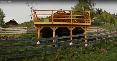 a house on a wooden stand next to a fence at Glamping hišice Orlič in Muta