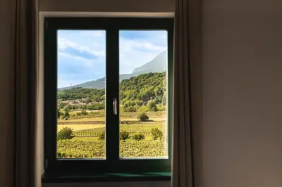 a window with a view of a field and mountains at Rooms&Vinery Bregovi - Sobe in vinska klet Bregovi in Dobravlje