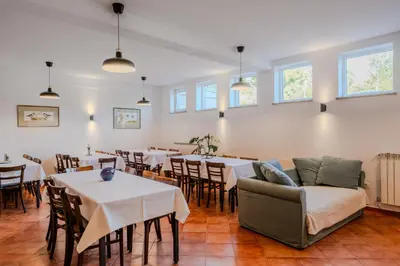 a dining room with tables and chairs and a couch at Rooms&Vinery Bregovi - Sobe in vinska klet Bregovi in Dobravlje