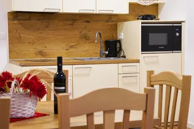 a kitchen with a sink and a table with a bottle of wine at Metropolitana's Zois Apartments in Bohinj