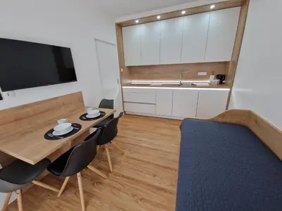 a living room with a table and chairs and a kitchen at Platinum Bled in Bled
