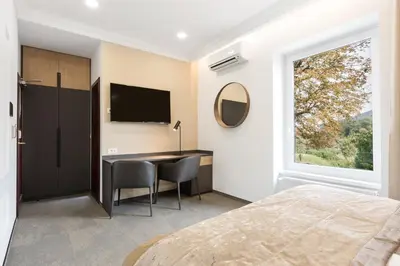 a bedroom with a desk and a large window at Garni Hotel Cirman in Ljubljana