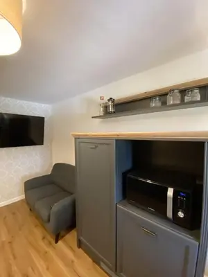 a living room with a flat screen tv and a chair at Ami's House Castle View in Bled