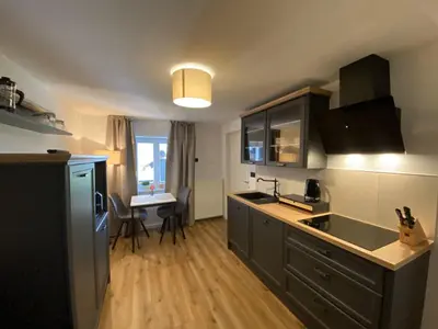 a kitchen with black cabinets and a table with chairs at Ami's House Castle View in Bled