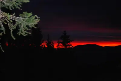 a sunset with trees and mountains in the background at Country House & Spa in Mislinja