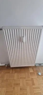 a white radiator in a room with a wooden floor at Thomas apartment 028 in Ljubljana