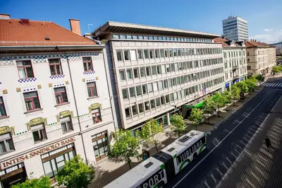 a train on a street in front of buildings at Central View Point Apartment in Ljubljana