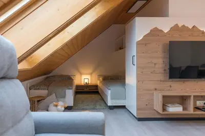 a loft bedroom with a bed and a tv at Hiša Rodica in Bohinj