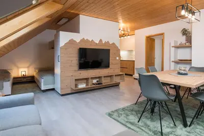 a living room with a dining table and a tv at Hiša Rodica in Bohinj