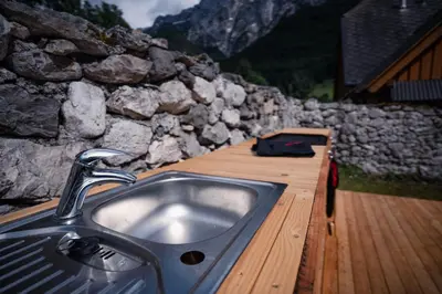 a sink in a wooden deck with a stone wall at Hostel Kronotop in Triglav National Park in Log pod Mangartom