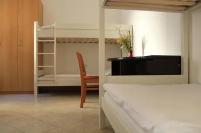 a bedroom with a bunk bed and a chair at Hostel Kronotop in Triglav National Park in Log pod Mangartom