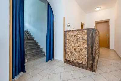 a hallway with blue curtains and a stone wall and stairs at Hostel Kronotop in Triglav National Park in Log pod Mangartom