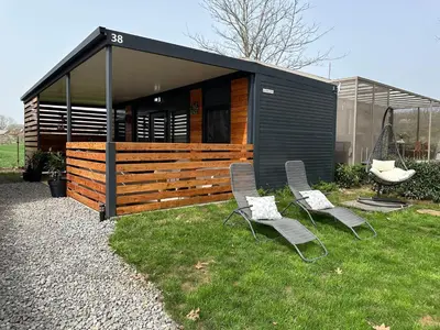 a small house with two chairs in the grass at MAGNOLIA HOUSE by the RIVER in Metlika