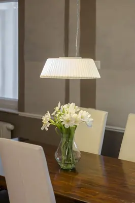 a vase of flowers on a table under a lamp at City Central in Ljubljana