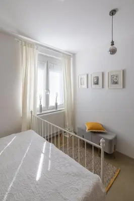 a white bedroom with a bed and a window at City Central in Ljubljana