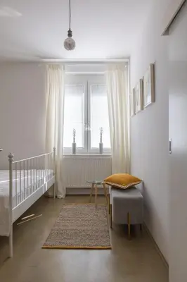 a white bedroom with a crib and a window at City Central in Ljubljana