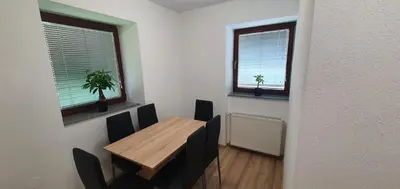 a dining room with a table and chairs and two windows at Apartment Podkuze in Mojstrana