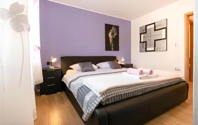 a bedroom with a large bed with purple walls at 3 Bedroom Awesome Home In Divaca in Divača
