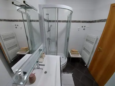 a white bathroom with a shower and a sink at APARTMA GONZO in Bovec