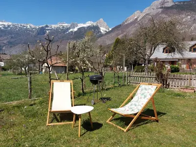 two chairs sitting in the grass with mountains in the background at APARTMA GONZO in Bovec