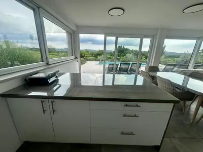 a kitchen with a table and a view of a pool at Villa Rosemary Trieste HerMes arT in Sežana