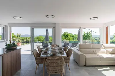 a living room with a white couch and a table and chairs at Villa Rosemary Trieste HerMes arT in Sežana