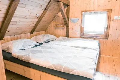 a large bed in a wooden room with a window at Počitniška hiška Jrga in Bovec