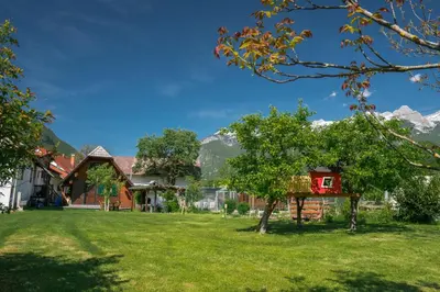 a house with a yard with mountains in the background at Počitniška hiška Jrga in Bovec