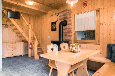 a dining room with a wooden table and a stove at Počitniška hiška Jrga in Bovec