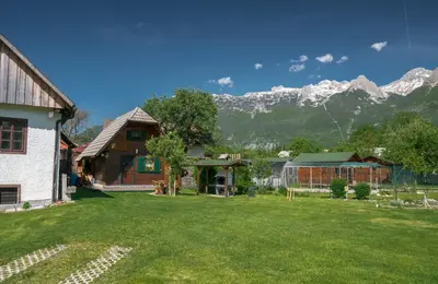 a house with a yard with mountains in the background at Počitniška hiška Jrga in Bovec