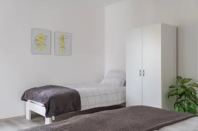a white bedroom with a bed and a plant at Apartma ODDIH in Dutovlje
