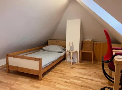 a bedroom with a bed and a chair in a attic at Apartment Malina - free private parking in Ljubljana