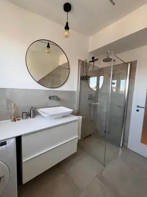 a bathroom with a sink and a shower with a mirror at Apartment Malina - free private parking in Ljubljana