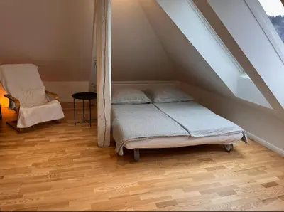 a bedroom with a bed and a chair in the attic at Apartment Malina - free private parking in Ljubljana
