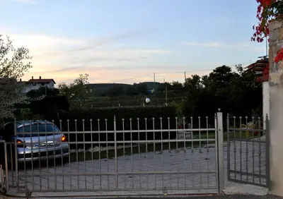 a fence with a car parked in a parking lot at Apartment in the heart of Brda wine region, Darinka Marinič in Dobrovo