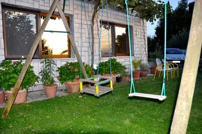 a yard with a swing and a bench in front of a house at Apartment in the heart of Brda wine region, Darinka Marinič in Dobrovo