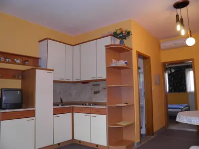 a kitchen with white cabinets and a sink and a tv at Pri štorklji in Moravske Toplice
